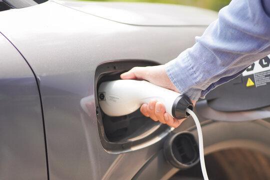 
Electric car charging at plug in charging station in a public car park. Renewable clean energy car for progressive eco awareness lifestyle concept.