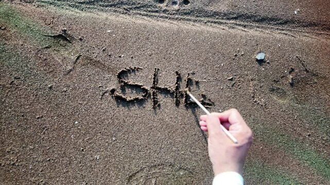 Hand writing sehe said yes in the sand on the beach. Wedding proposal. 