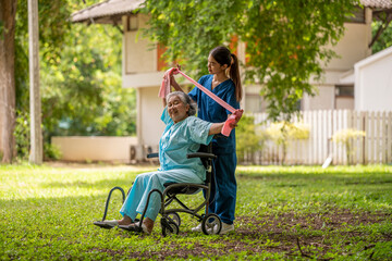 Fototapeta premium Healthcare or physical therapy nurse is helping elderly woman in performing a stretching or rehabilitation exercise with a resistance band caregiver individuals focused rehabilitation elderly concept.