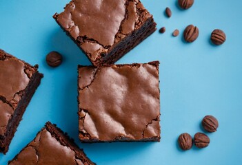 Close-up of two brownie pieces on a blue background, top view. Dessert photography, chocolate treat, baked goods, sweet indulgence, delicious brownies. Ai generated image
