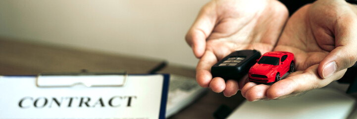 Car dealer salesman handed new car buyer while signing the contract..