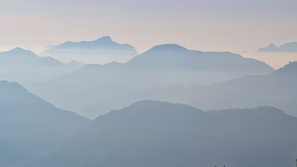 Serene alpine landscape at dawn in Gailtal Alpen, Carinthia, Austria, Europe. Silhouette of majestic hazy mountain ridges of Julian Alps. Peaceful tranquil atmosphere in Austrian Alps. Wanderlust