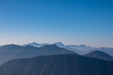Serene alpine landscape seen from Latschur in Gailtal Alpen, Carinthia, Austria, Europe. Silhouette of majestic hazy mountain ridges of Julian Alps. Peaceful tranquil atmosphere. Wanderlust. Freedom