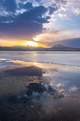 冬の氷った湖の朝陽。水面に反射する夜明けの空。北海道の屈斜路湖。