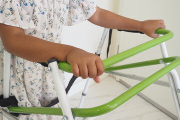 A Child Utilizing a Green Walker Designed for Support and Improved Mobility Skills