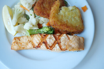 Delicious grilled salmon accompanied by a side of mixed vegetables and crispy hash browns