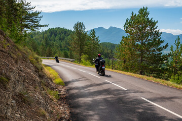 two men on motorbikes on a road in the mountains of Vercors in France
