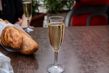 a glass of sparkling white wine on a table with a french baguette in the background