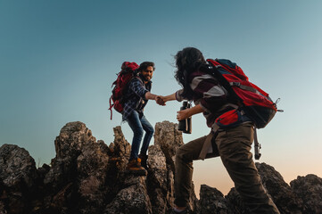 Two people are helping each other climb a mountain