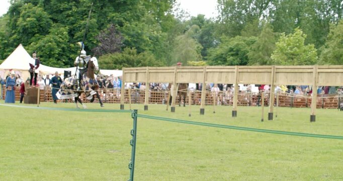 4K slow motion shot of the clashing of lances of mounted knights in full suit of armour, at the Queen's Joust tournament at Leeds Castle, Kent, England