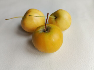 Close-up of ranetki apples. Small yellow apples on a white background. Apple dishes concept. Background, space for text. Benefits of yellow apples.