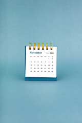 November 2024 white desk calendar on blue background.