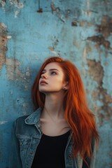 Obraz premium Woman with Red Hair Leaning Against Blue Wall