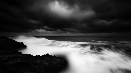 Obraz premium Ocean's Fury in Monochrome: A dramatic black and white seascape captures the raw power of nature as waves crash against a rocky shore beneath a brooding sky. 
