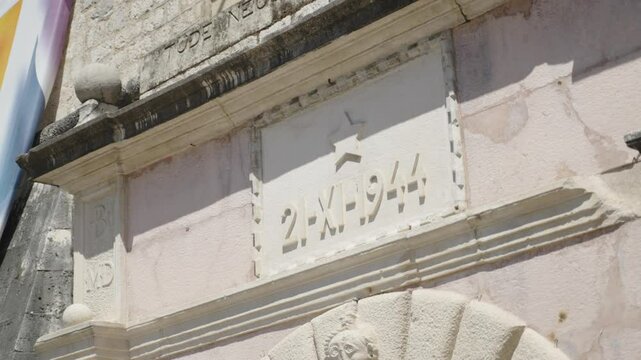 Close up of inscription above the sea gate entrance of the city walls old town in Kotor Montenegro showing a start and 21 - XI - 1944 detail historical military building