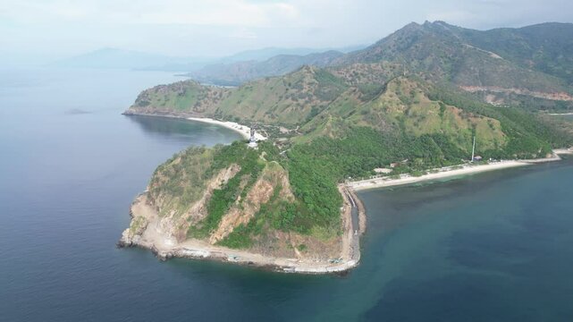 A coastal peninsula with green hills and blue water in timor-leste during the day, aerial view