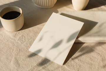 A blank piece of card on a table with ceramics, a cup of black coffee in sunlight.