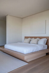 Modern bedroom with an elegant low profile bed, minimalist decor window lighting and ample copyspace. Stylish resting interiors composition.