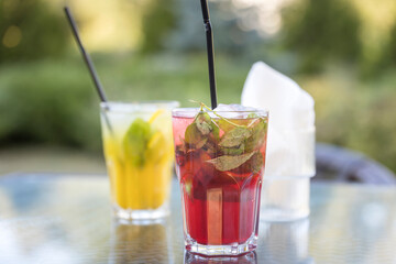 Two drinks on a table, one is a pink drink and the other is a yellow drink