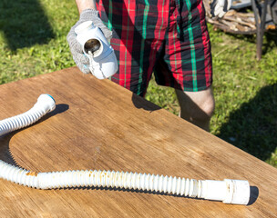 A man is holding a white pipe on a wooden table