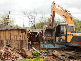 Fototapeta premium yellow excavator demolishes old buildings with its bucket