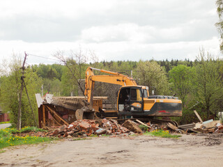 Fototapeta premium yellow excavator demolishes old buildings with its bucket