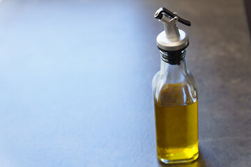 glass jar with extra virgin olive oil on an illuminated table in blue and copy space