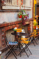 Empty garden chairs table outdoor cafe on side oroad near old house 