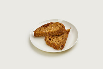 Two slices of toasted bread on a white plate. The bread is golden brown and crispy, and the plate is set against a clean white background.