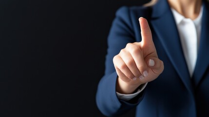 A businesswoman in a blue suit gestures with her finger raised, symbolizing importance or a call for attention against a dark background.