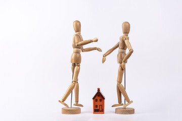 2 wooden mannequins depicting a couple arguing about a house, isolated on white background. Copy space. Concept of housing, couple and conflict