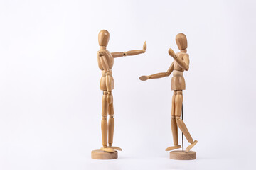 2 wooden mannequins representing an arguing couple, one of them making stop gesture with hand, isolated on white background. Copy space. Concept of discussion and conflict