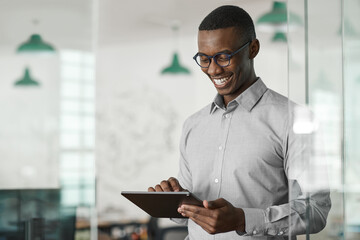 Smiling young African businessman using a digital tablet at work