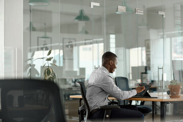 Smiling African businessman using a tablet at an office table