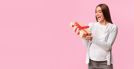 Baby Shower Concept. Joyful Pregnant Lady Holding Wrapped Gift Box Standing Over Gray Studio Background. Panorama, Free Space