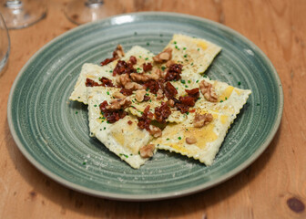 Plate of ravioli stuffed with mushrooms and parmesan, with dried tomato sauce