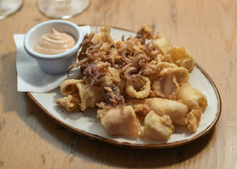 Una ración de calamares fritos con salsa de ajo en un restaurante europeo.