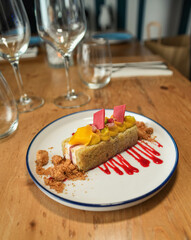 Un trozo de pastel con fruta en un plato blanco en un restaurante.