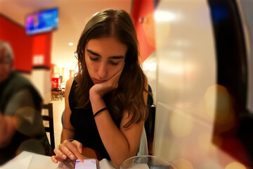 Young beautiful woman sitting at a table in a cafe