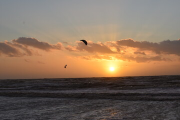 Ein Kitesurfer fliegt in den Sonnenuntergang