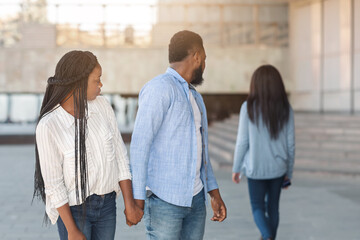 Fototapeta premium Infidelity concept. Black millennial guy distracted to another woman while walking with his girlfriend in city, selective focus