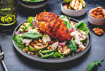 Foodie grill salad with zucchini and chicken, feta cheese, walnuts, red onion and spinach, black background, top view