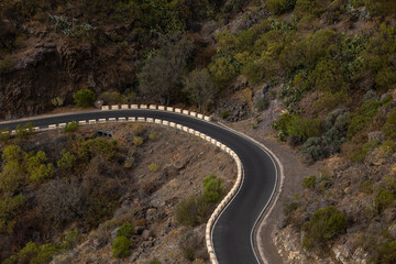 Mountain pass one-way curving road with cliffs on either side passing through the middle of the countryside.