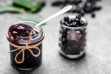 Aronia jam and fresh berry on stone table.