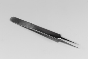 Steel tweezers with pointed tips on a gray background