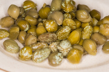 Pickled capers on a saucer, side view in selective focus