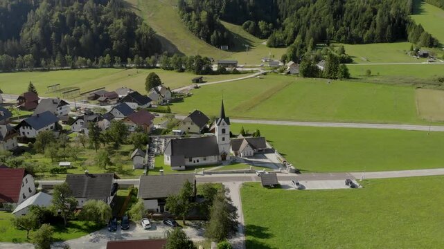 4K drone footage of Cerkev Sv. Andrej Church in Podkoren, Slovenia, with stunning views of Visoka Ponca and Visoka Peč in the background. Perfect for nature, travel, and architectural projects.