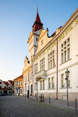 Obraz premium The historic Town Hall stands proudly in Stara Boleslav, showcasing elegant architecture under the golden light of dusk. Cobbled streets invite visitors to explore the charming surroundings.