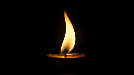 A single candle flame burns brightly in the darkness.