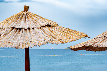 Straw parasols on blue sky and sea background with copy space